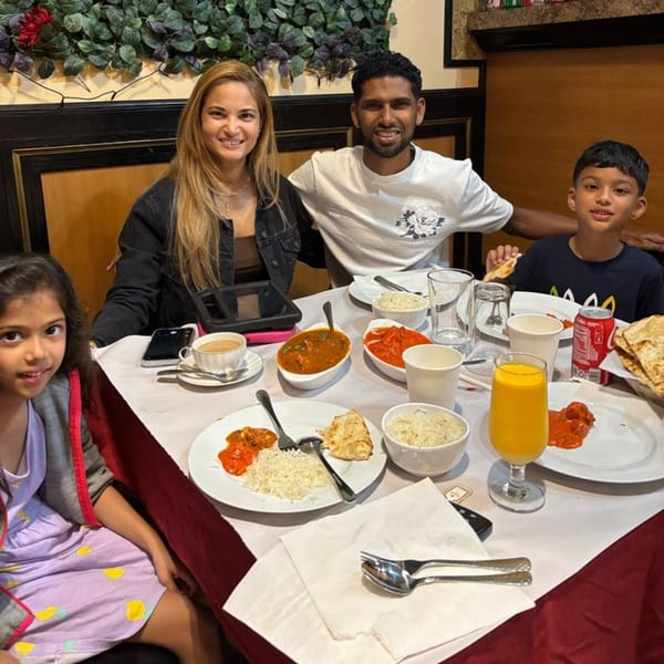 A family of four smiles at the camera while enjoying Indian food at Sajna Indian Cuisine.